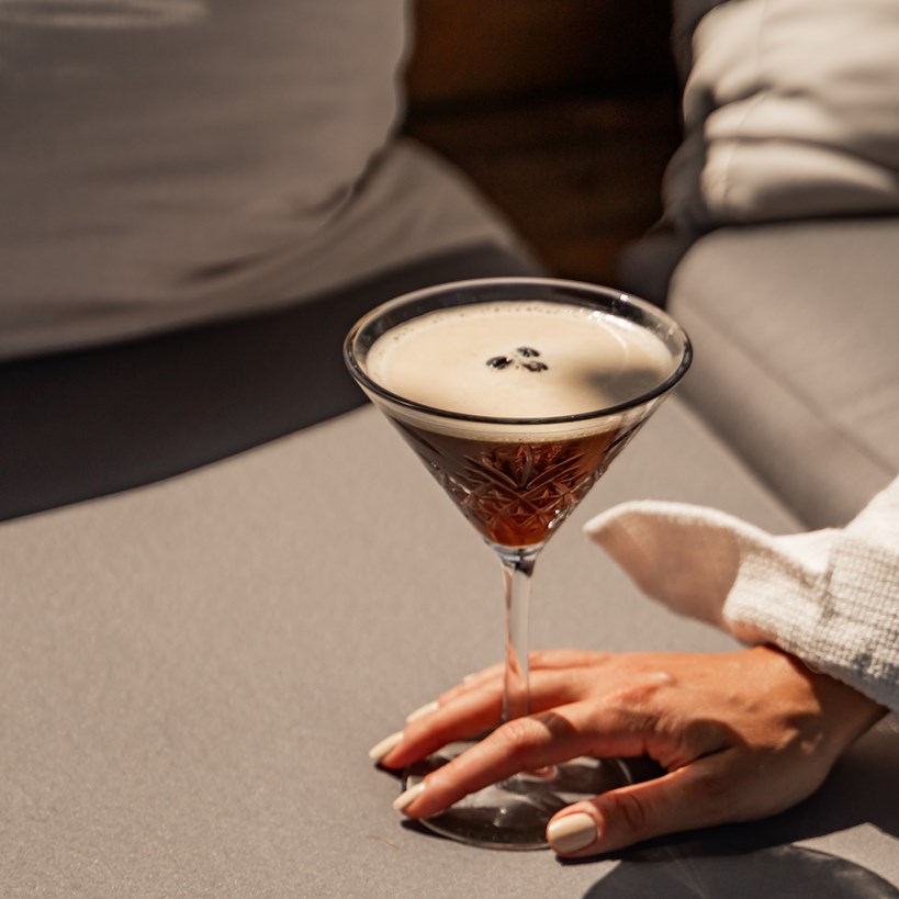 Espresso Martini Cocktail resting on a couch cushion in the sun